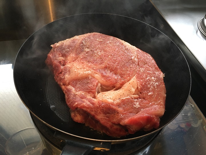 鉄のフライパンで肉を焼く